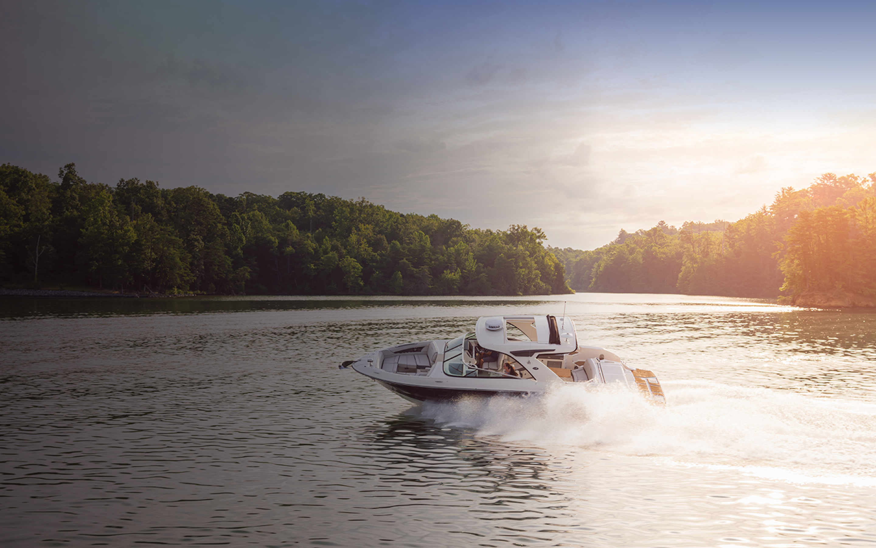 A white boat driving on a lake.