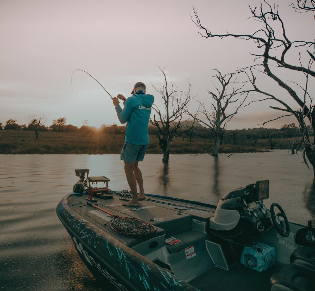A man reeling in a fish while standing on a kayak.