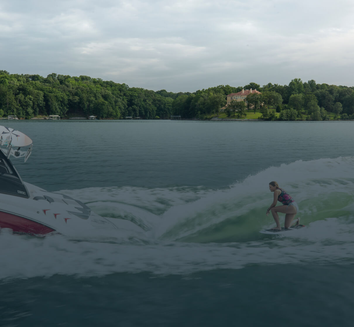 A person surfing the wake of a boat on a lake.