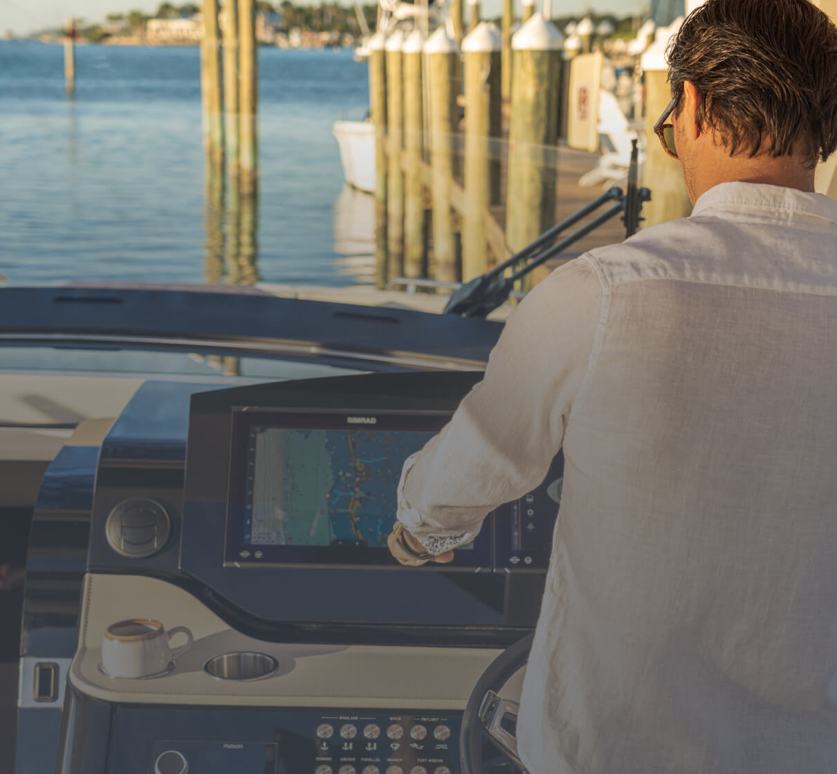 A person driving a boat while looking at digital Simrad® navigation screens.